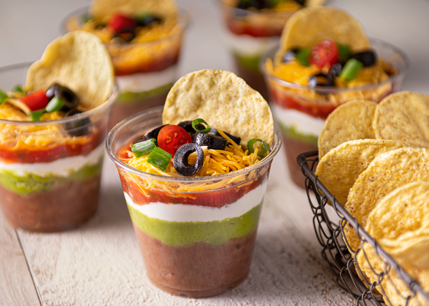 Cups of guacamole, queso, and salsa with chips.