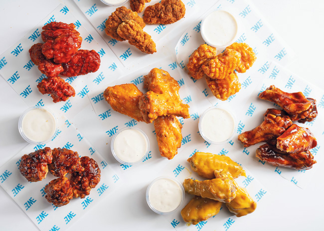 Several different styles of chicken wings, each with a creamy dip.